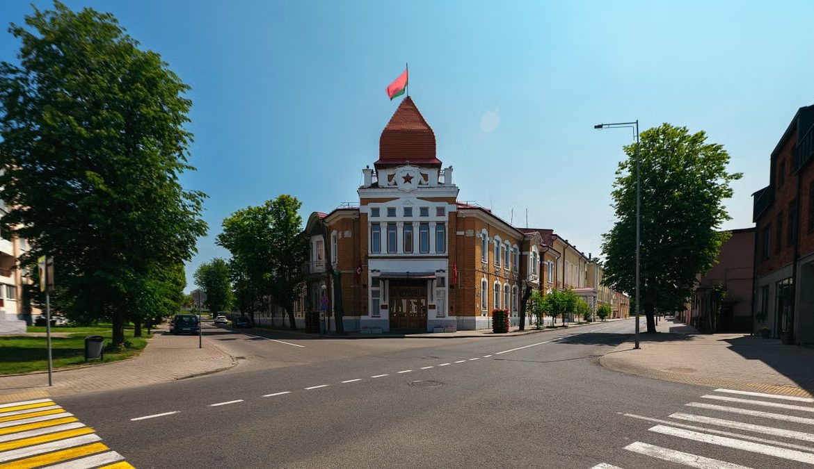 An empty street featuring a historic building with a red flag under a clear sky.