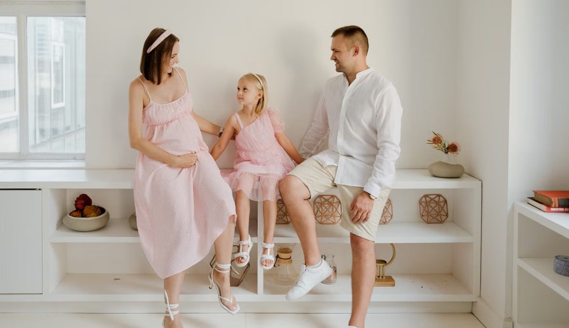 A joyful family of three sitting together indoors with smiles and warmth.